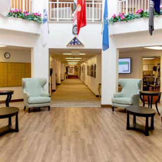 A decorated lobby area featuring chairs, a hallway, and various flags displayed above.
