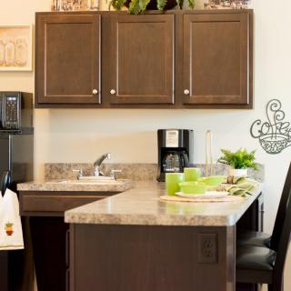 A modern kitchen with a marble countertop, wooden cabinets, and a coffee maker.