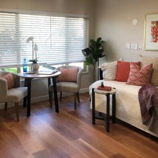 A cozy living room with modern decor, featuring a sofa, a small table with chairs, and a wooden floor.