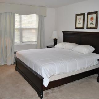 A tidy and well-decorated bedroom with a large bed and framed artwork.