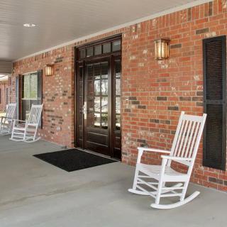 A welcoming porch with white rocking chairs and a brick exterior.