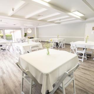 A bright, spacious event space with neatly arranged tables and chairs.