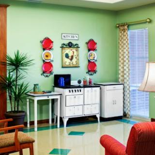 A stylish vintage-inspired living room showcasing green walls, retro furniture, and decorative artwork.