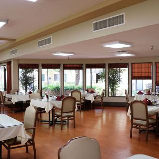 A spacious dining area with neatly arranged tables and chairs, featuring large windows.