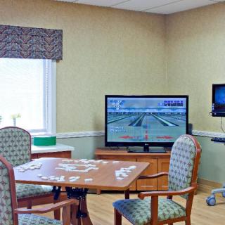 A cozy room with a puzzle on the table, chairs, and a television.