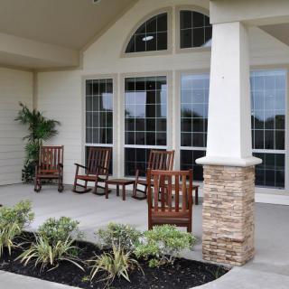 A welcoming porch area with wooden rocking chairs and potted plants.