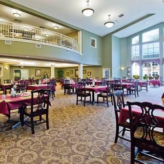 Spacious dining area with elegantly arranged tables and chairs, featuring large windows and stylish lighting.
