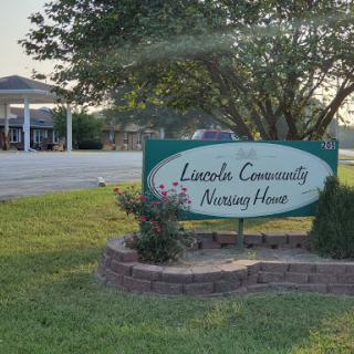 A sign indicating the Lincoln Community Nursing Home, surrounded by greenery.