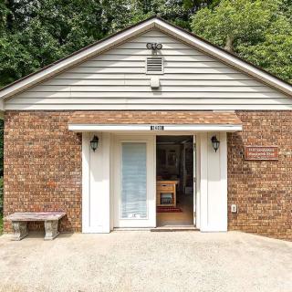 Front view of a brick building with an open entrance and a small bench to the side.