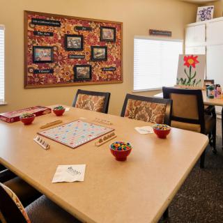 A cozy meeting room with a Scrabble game set up on a table, surrounded by chairs and decorated with colorful artwork.