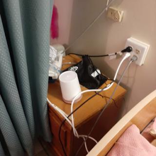 A close-up view of a bedside table with various charging cables and a power outlet.