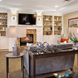 A cozy living room featuring a fireplace, built-in bookshelves, a comfortable sofa, and a flat-screen TV.