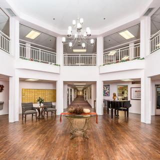 Spacious and elegant lobby with a chandelier, wooden flooring, and a grand piano.