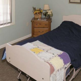 A bedroom with a hospital bed and a nightstand beside it.