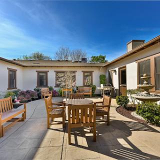 A spacious outdoor patio featuring wooden furniture under a clear blue sky.