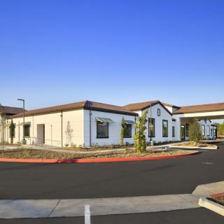 A modern building with a driveway and clear blue sky.