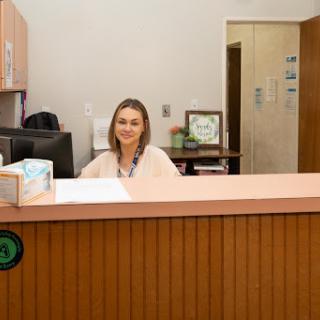 A friendly receptionist sitting at a desk, ready to assist visitors in an office setting.