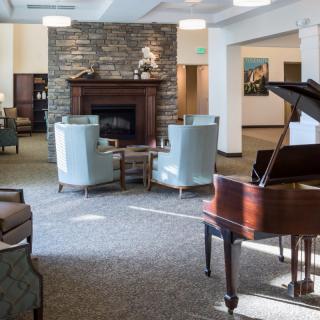 A cozy living room featuring a piano and a fireplace surrounded by comfortable chairs.