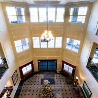 A spacious hotel lobby with a high ceiling, featuring a chandelier and a decorated Christmas tree.