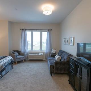 A cozy living space featuring a sofa, bed, and large window with natural light.