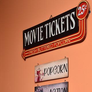 Vintage movie theater sign advertising tickets for 25 cents and popcorn.
