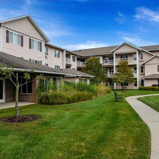 A peaceful apartment complex surrounded by greenery and a clear blue sky.
