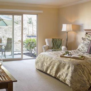 A cozy bedroom with a view of a sunny patio through sliding glass doors.