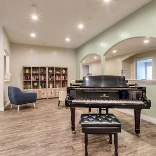 A stylish living room featuring a grand piano, bookshelf, and modern furnishings.