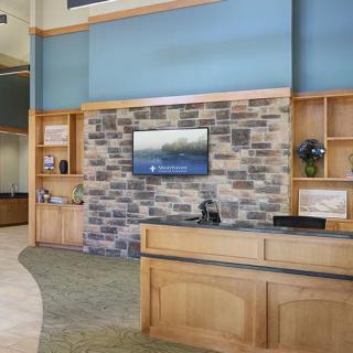 A modern reception area with a stone accent wall and a mounted television.