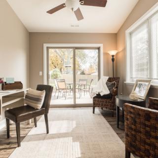 A cozy home office with a desk and chairs, featuring ample natural light from a sliding door.