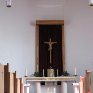 A church interior featuring an altar with a crucifix and candles.