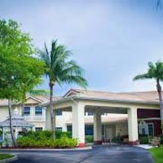 A building with palm trees and landscaped grounds at the entrance.