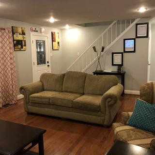 A cozy living room with a sofa, coffee table, and a staircase leading to the upper floor.