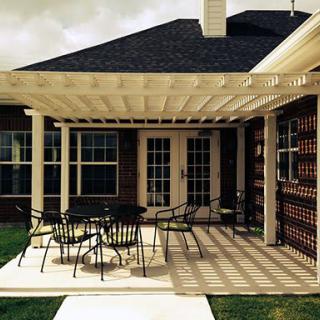 A backyard patio with a pergola providing shade, featuring outdoor furniture for relaxation.