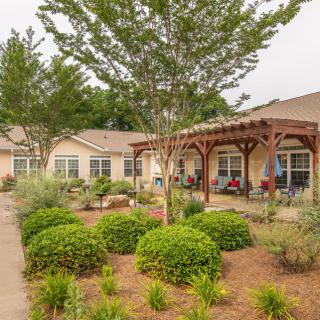 A well-landscaped garden with a patio in front of a building.