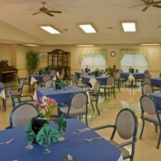 A spacious dining area with tables covered in blue tablecloths and floral centerpieces.