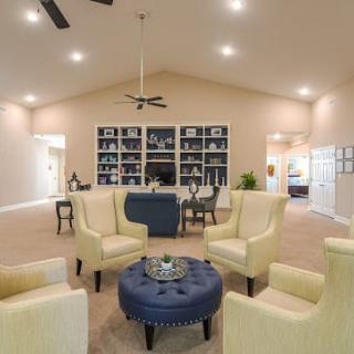A well-decorated living room with modern furniture, including yellow armchairs, a blue ottoman, and built-in bookshelves.