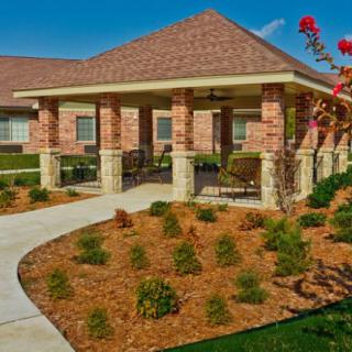 A well-landscaped brick house with a covered porch and a walkway leading to the entrance.