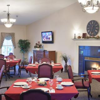 A cozy dining room with elegant table settings, a fireplace, and chandeliers.