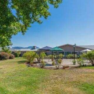 A scenic outdoor garden area with a patio under a clear blue sky, surrounded by lush greenery.