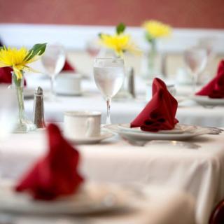 An elegantly set table with red napkins and yellow flower centerpieces.