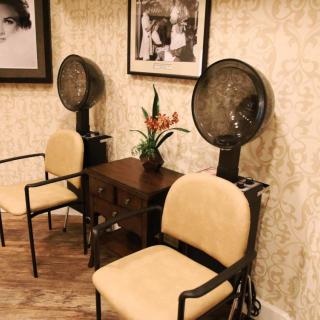 A cozy waiting area in a salon featuring vintage hair dryers and stylish seating.