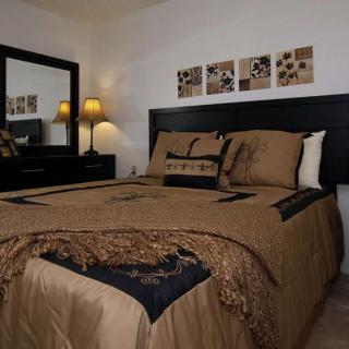 A cozy and well-decorated bedroom with elegant bedding, a mirror, and ambient lighting from lamps.