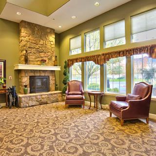 A cozy living room featuring a stone fireplace, large windows, and traditional furnishings.
