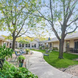 A peaceful courtyard with trees and a winding pathway lined with chairs.