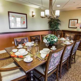 A formal dining room with a large table set for a meal, featuring elegant decor and a floral centerpiece.