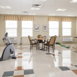 A spacious rehabilitation room with exercise equipment and a cozy seating area.