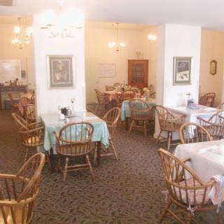 A cozy restaurant dining area with traditional wooden tables and chairs, warmly lit and beautifully decorated.
