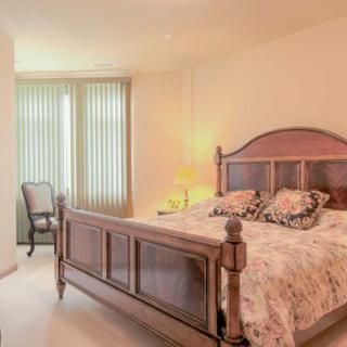 A cozy bedroom with a wooden bed, a side lamp, and vertical blinds covering the window.