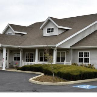 A suburban residential building with a gabled roof and neatly trimmed hedges.